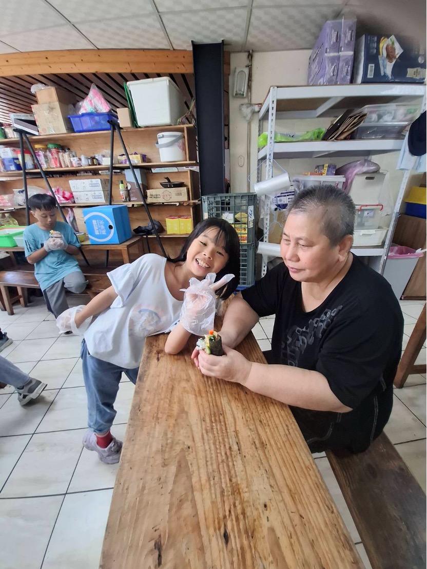 孩子笑著把手卷遞給阿嬤一起享用